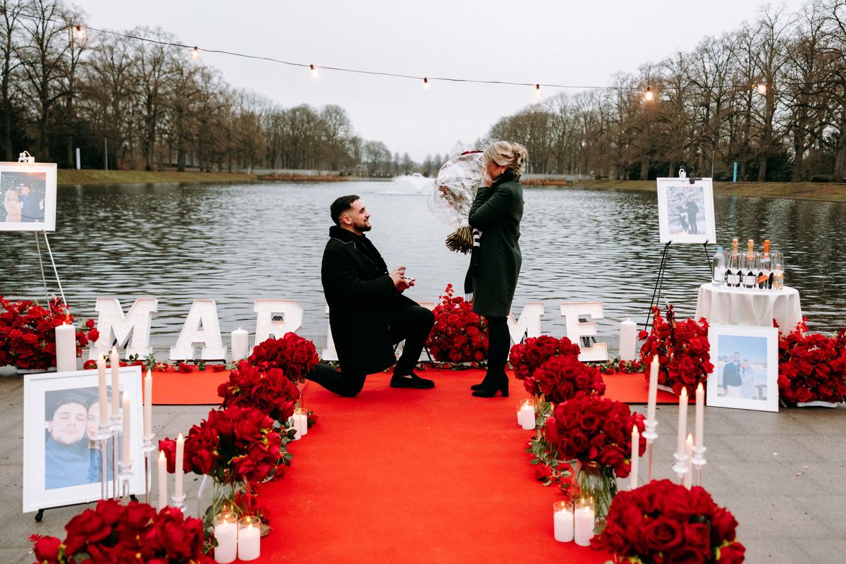 Heiratsantrag am See rote Rosen leuchtende Marry Me Buchstaben
